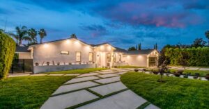 A modern-looking home that has a driveway and pathways that use separated sections with grass in between.