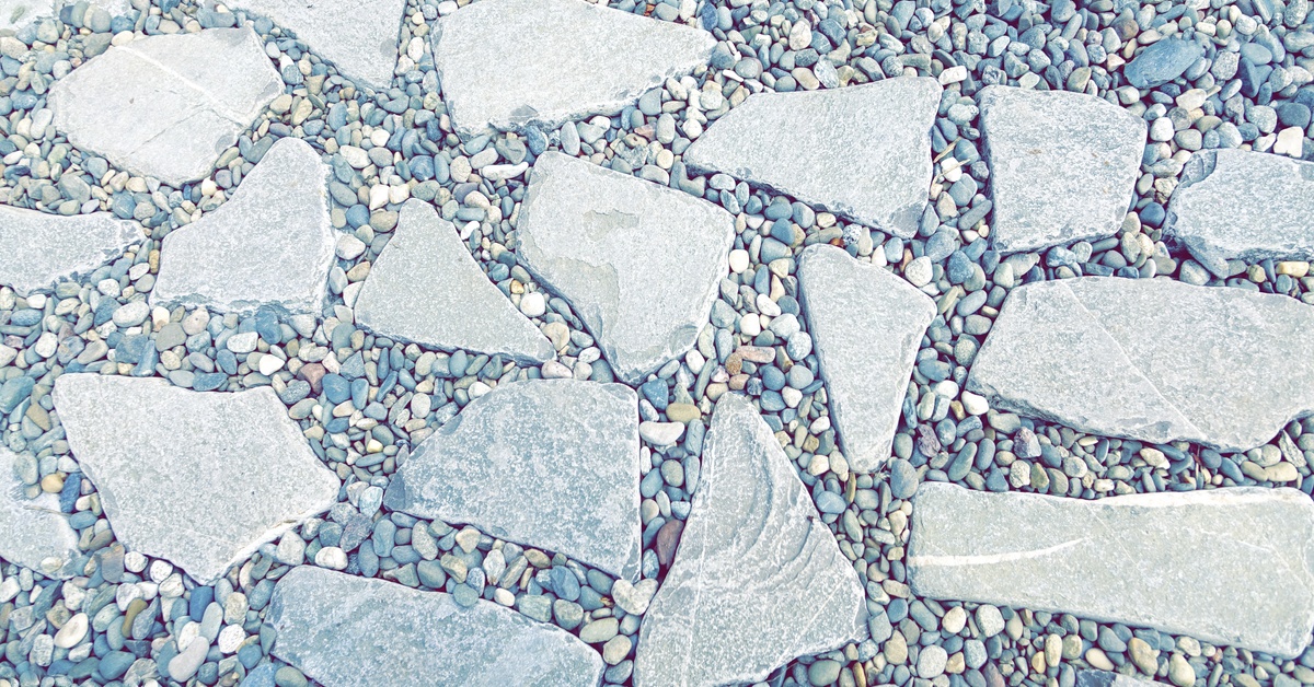 A flagstone walkway filled with small round pebbles form a decorative patterned surface for an outdoor pathway.
