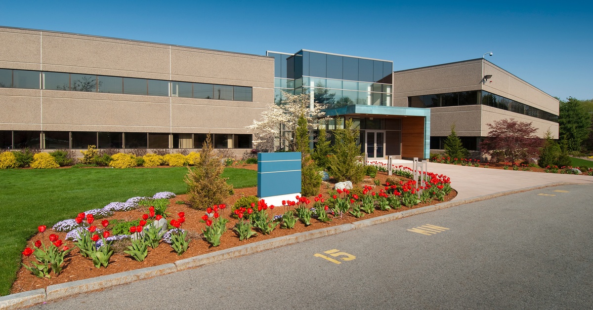 A modern commercial building features two stores, several large windows, a landscaped entrance, and an entryway.