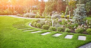 A beautifully landscaped residential backyard features several paved walkways around flower beds.