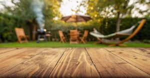 A close-up view shows the wooden planks that create a wooden deck in the backyard of a home. The background is blurry.
